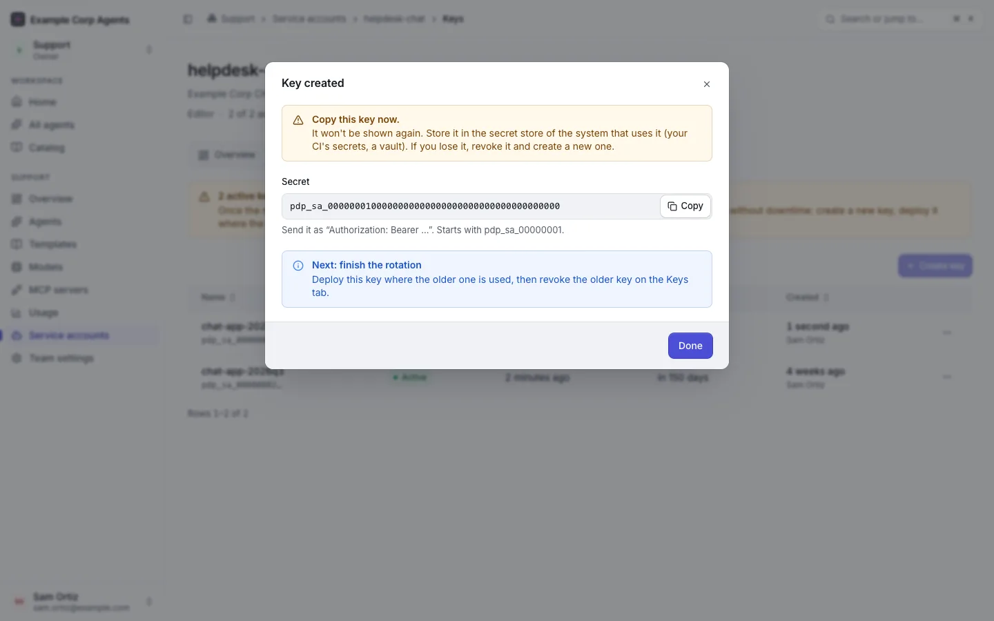 The "Key created" dialog for the helpdesk-chat service account: "Copy this key now.", the secret in a copy field with the hint that it starts with pdp_sa_00000001, and "Next: finish the rotation".